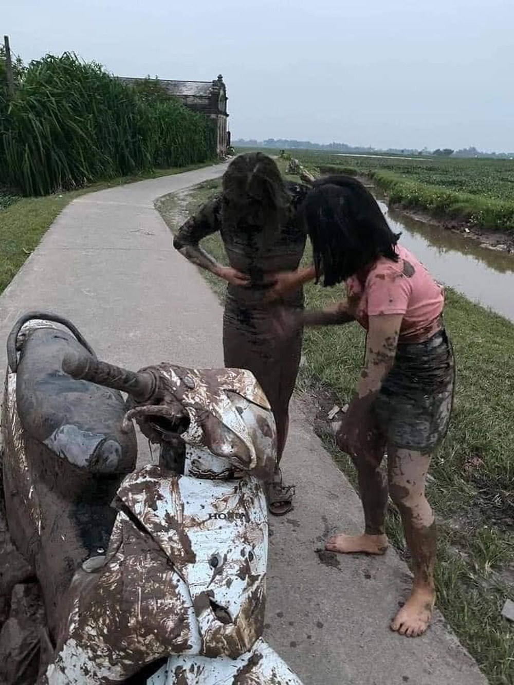 Lao xe máy xuống ruộng, 2 cô gái diện váy bó nhuốm đầy bùn, biểu cảm trái ngược gây chú ý - Ảnh 1.